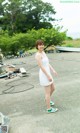 A woman in a white dress standing in a parking lot.